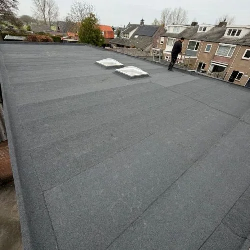 Platdak renovatie in Woerden met nieuw dakbeschot, 80 mm PIR isolatie, bitumen dakbedekking en vernieuwde dakkoepels.